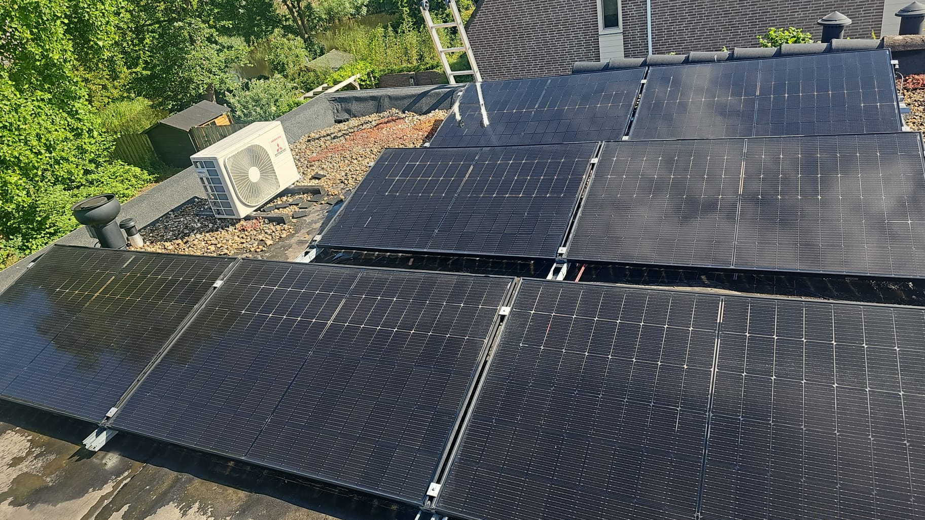 Zwarte zonnepanelen op een plat dak tijdens de reiniging, met ladder en airco