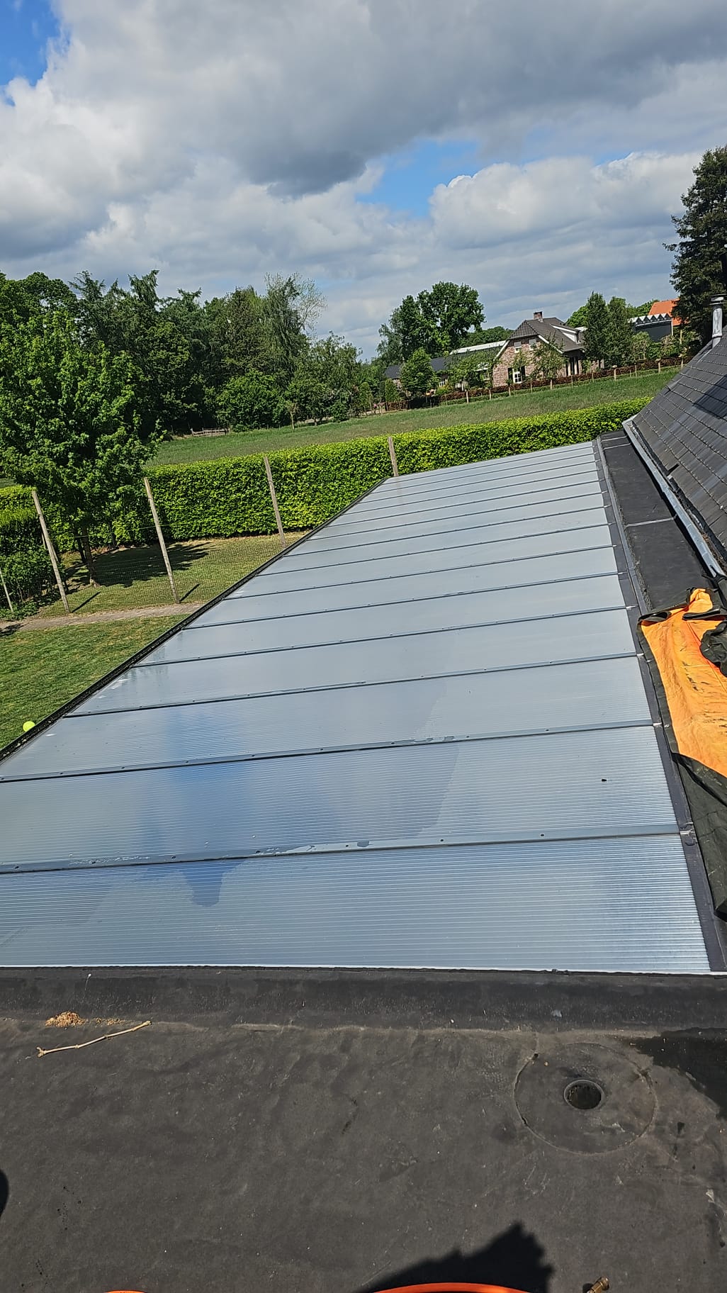 Lange glazen lichtstraat na de reiniging, met de tuin en lucht erachter