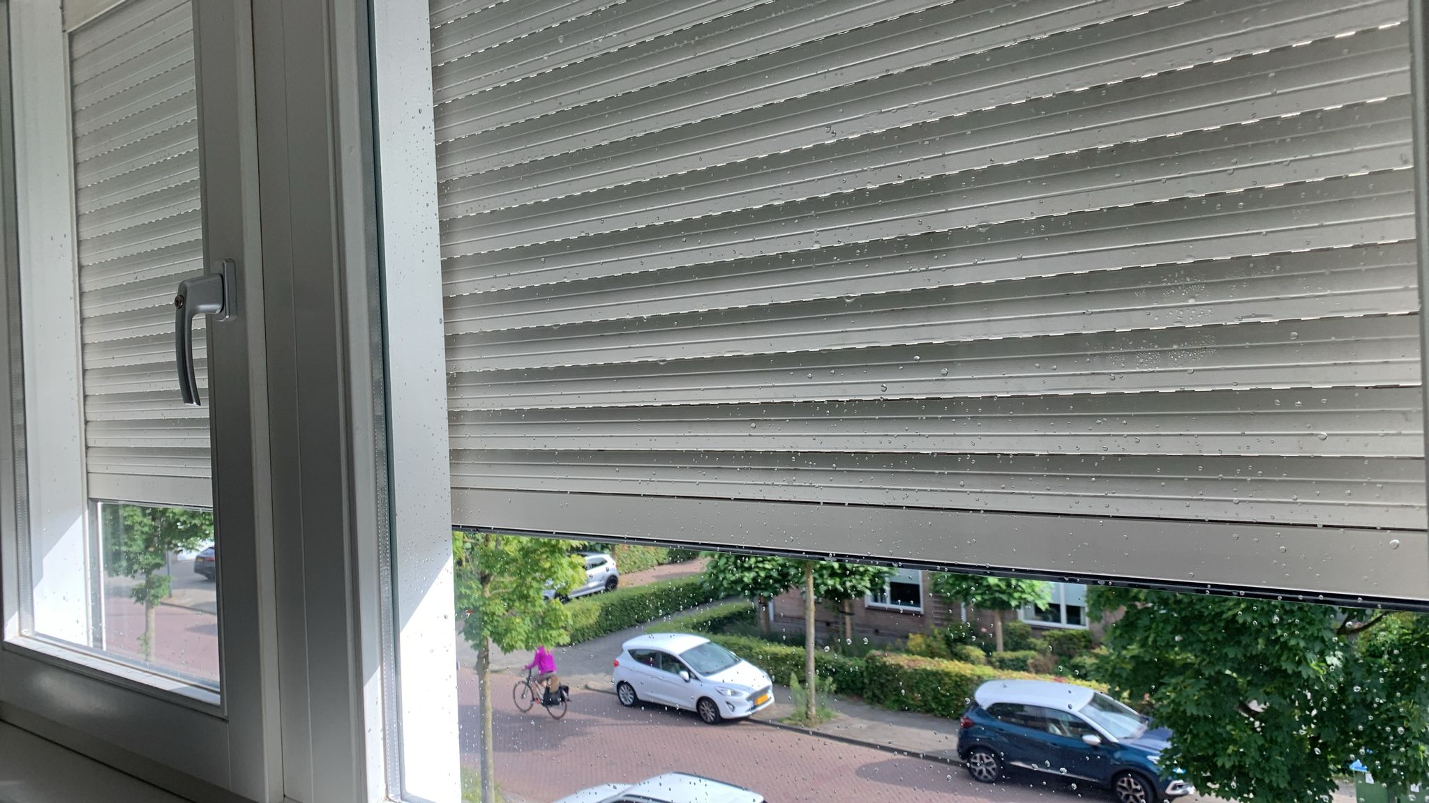 Schoon raam met rolluik, uitzicht op de straat