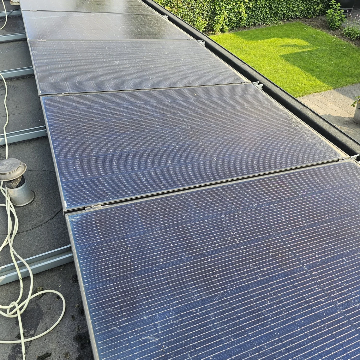 Zonnepanelen op een plat dak, met gazon ernaast